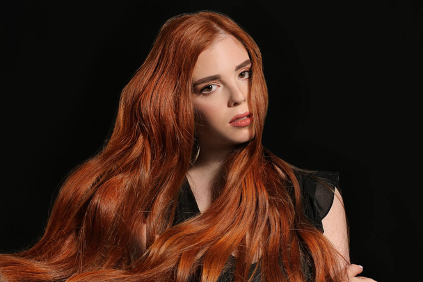 Beautiful young redhead woman on dark background - Фото, изображение