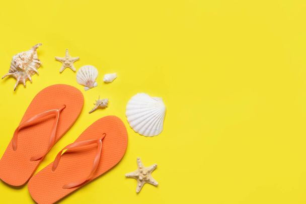 Stylish flip-flops and sea shells on color background - Photo, Image