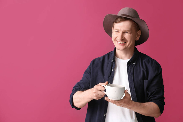 Handsome man with cup of tea on color background - Фото, зображення