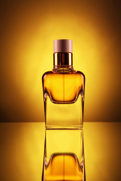 黄色の背景に金色の香水と透明なボトル。垂直. - 写真・画像
