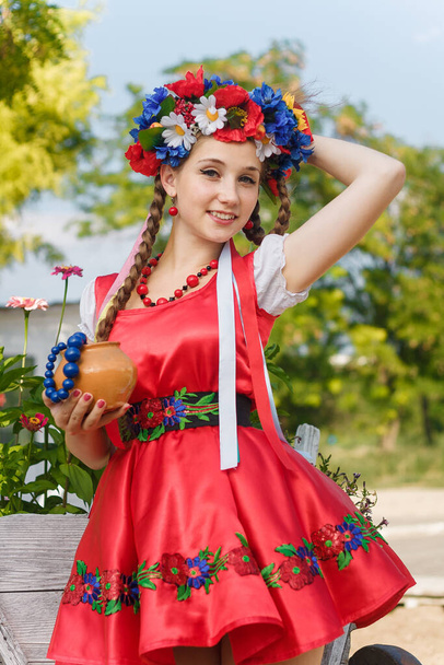 Tyttö kaksi punokset Ukrainan perinteinen mekko, kukat seppele nauhat, punainen korvakorut ja helmiä tilalla savi potin.  - Valokuva, kuva