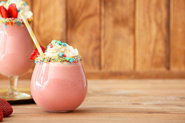 Стакан вкусного клубничного молочного коктейля на столе
 - Фото, изображение