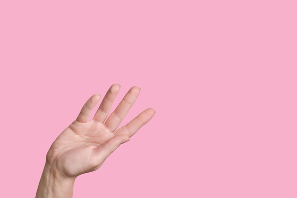 Caucasian hand waves while. Farewell gesture. Pink background. - Foto, imagen
