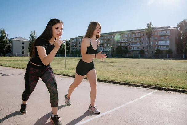 Two athletes at the starting position in the stadium. Athletic girls run in the stadium.Girls are doing exercises, stretching. Sport and healthy lifestyle. - Foto, immagini