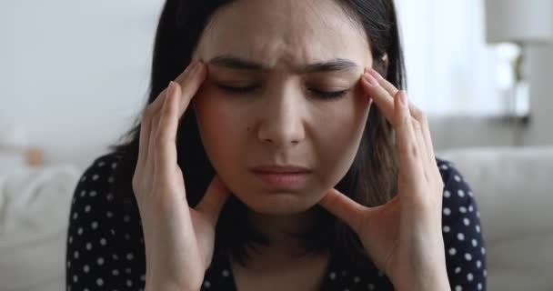 Unhappy asian woman suffers from headache chronic migraine closeup view - Imágenes, Vídeo