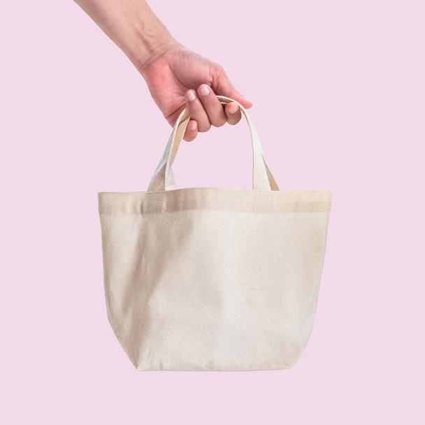 Bolso de mano tela de tela de algodón blanco para eco hombro bolsa de compras maqueta en blanco plantilla aislada sobre fondo rosa (ruta de recorte) con correas de manija de la mano de la mujer
 - Foto, Imagen