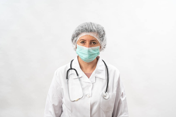 Tired female medic, nurse in protective equipment and a mask from viruses, on a white background. With a stethoscope. - Photo, Image