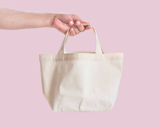 Tote taška plátno bílá bavlněná tkanina tkanina pro eko rameno nákupní pytel maketa prázdný šablona izolované na pastelové růžové pozadí (výstřižek cesta) s ženskou ruční rukojetí řemínky - Fotografie, Obrázek
