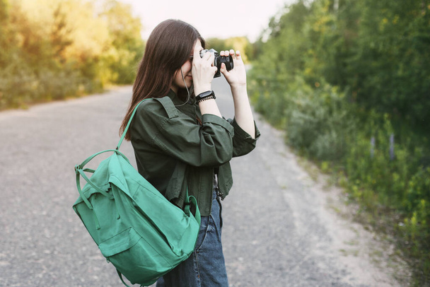 Morena bonito olha para a lente da câmera. Uma rapariga fotografa a natureza. Vista lateral, espaço para texto
 - Foto, Imagem