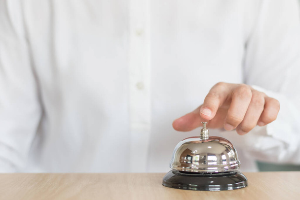 Servicio de campana del restaurante del hotel en el mostrador de recepción del cliente del conserje con la persona de negocios que suena presionando el botón de campana que pide ayuda
  - Foto, imagen