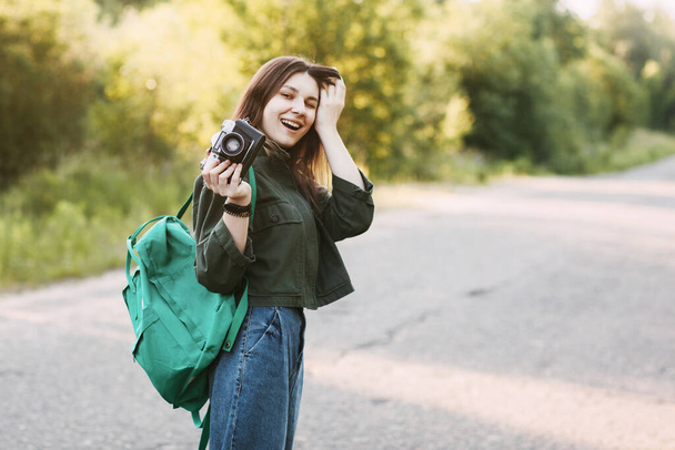 Una chica sonriente sostiene una cámara en sus manos. La chica viaja y toma fotos de paisajes en una cámara vintage. Espacio para texto
 - Foto, imagen