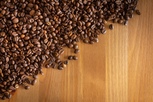 Coffee beans scattered on a wooden table. - Photo, Image
