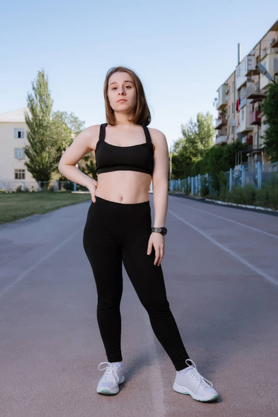 Portrait of attractive sport woman in sportswear posing outdoors at the stadium.young woman dressed in sportswear posing at the stadium on running track. Sport and healthy lifestyle. - Zdjęcie, obraz