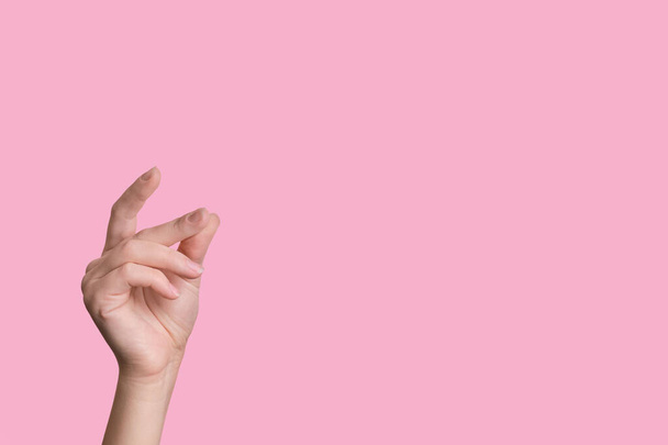 Female beautiful caucasian hand snaps fingers. pink background. - Foto, imagen