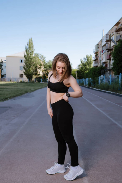 Portrait of attractive sport woman in sportswear posing outdoors at the stadium.young woman dressed in sportswear posing at the stadium on running track. Sport and healthy lifestyle. - 写真・画像