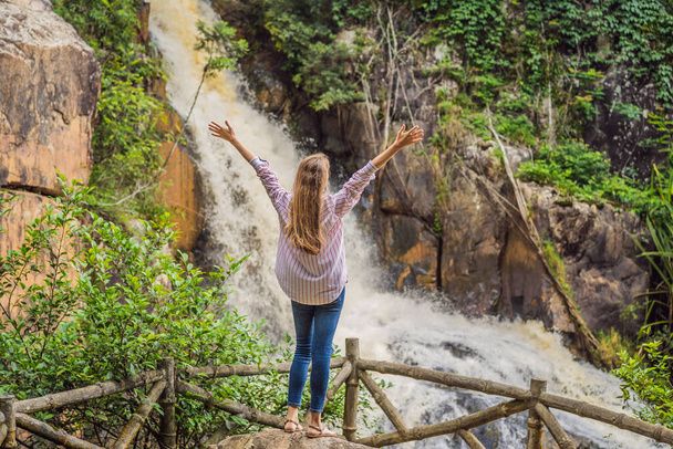 Молода жінка стоїть біля водоспаду в лісі. Чоловічий пішохід на природі
 - Фото, зображення