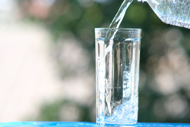Egy pohár víz a fa asztal háttér és öntött ivóvíz - Fotó, kép