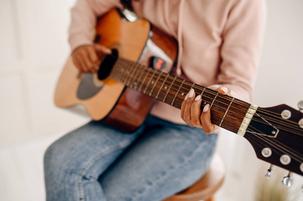 Una donna suona la chitarra a casa, vista da vicino. Bella signora con strumento musicale rilassarsi nella stanza, amante della musica femminile riposo - Foto, immagini