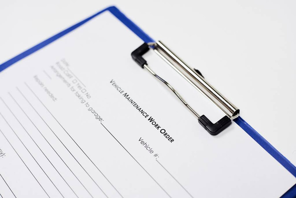 A closeup of a document entitled Vehicle Maintenance Work Order Form on a blue clipboard - 写真・画像