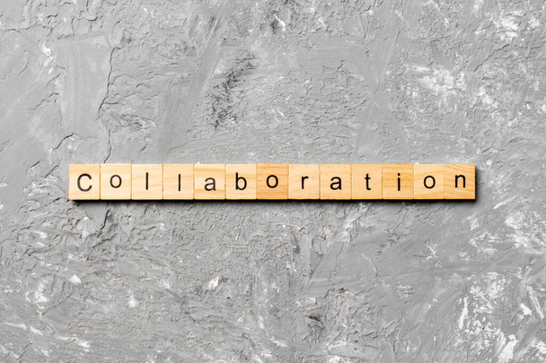 Słowo kolaboracji napisane na drewnianym bloku. Tekst współpracy na stole cementowym do projektowania, koncepcja. - Zdjęcie, obraz