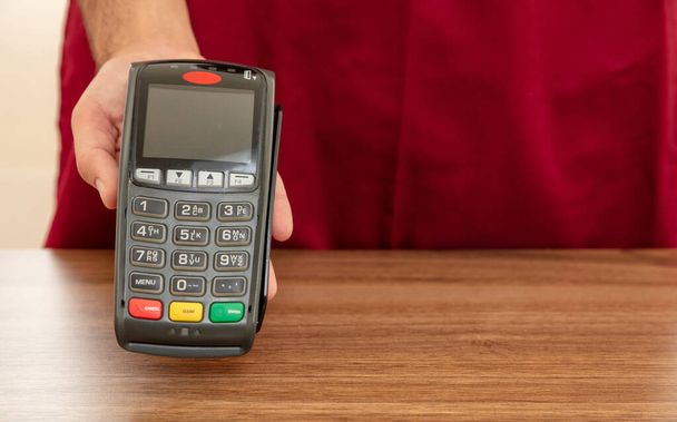 Cajero ofrece terminal de punto de venta para el pago con tarjeta de crédito. Banca, compras y pago sin contacto con el concepto de tecnología NFC
. - Foto, Imagen