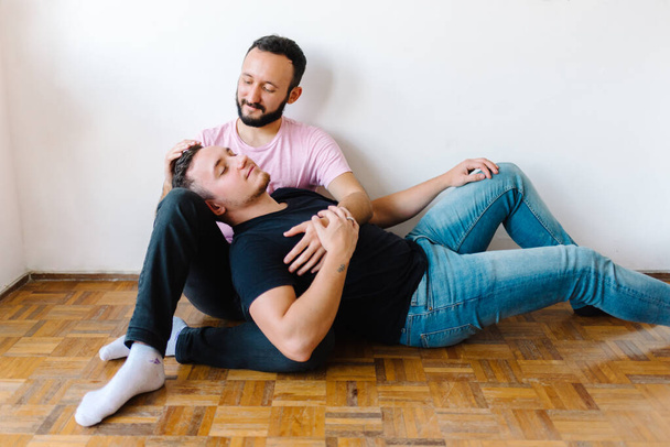 Készletkép két fehér homoszexuális férfiról. Egyikük leül, a másik az ölében fekszik.. - Fotó, kép