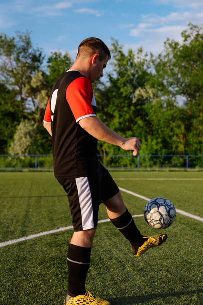 Młody mężczyzna piłkarz żongluje piłką na boisku piłkarskim.Athlete żonglowanie piłką nożną z jego stóp na stadionu.Football koncepcja sportowa - Zdjęcie, obraz