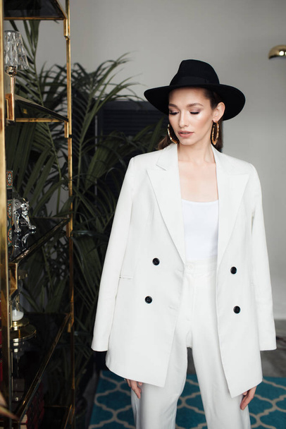 Young girl in a white suit and a black hat. The concept of clothing. - Photo, Image