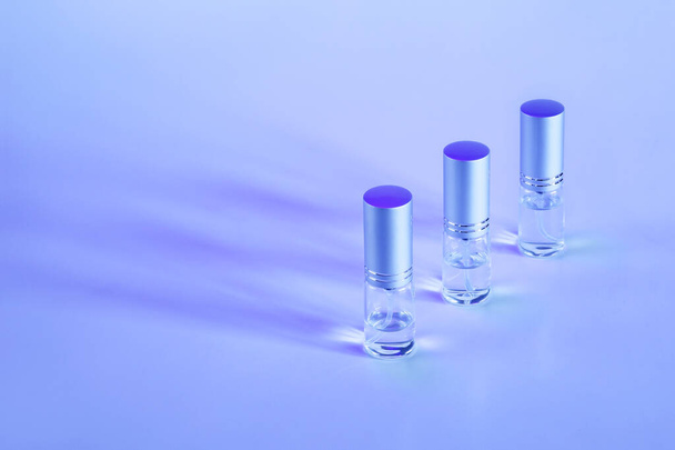 Tre mini bottiglie spray diagonalmente di fila su uno sfondo viola con spazio di copia - Foto, immagini