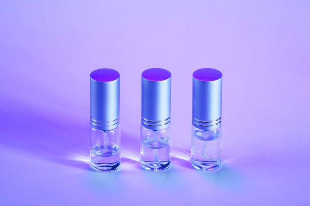 Три міні пляшки розпилення поспіль на фіолетовому фоні з копіювальним простором
 - Фото, зображення