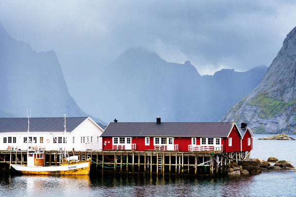 Kuuluisa matkailukohde Hamnoy kalastajakylä Lofoten Islands, Norja punainen ja keltainen rorbu taloa. Rauhallinen, sumea vesi - Valokuva, kuva