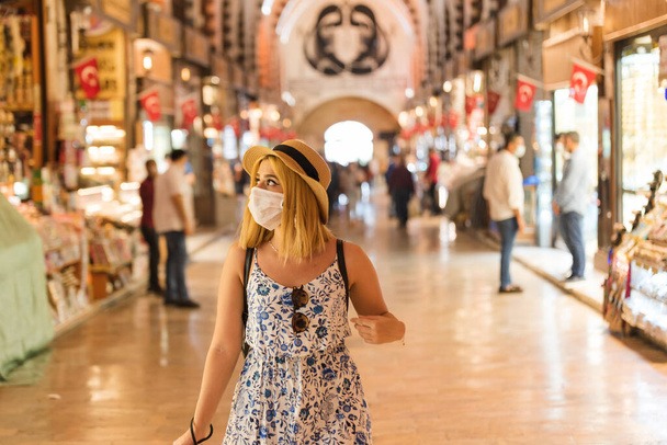 Beautiful tourist woman wearing disposable face mask walks in Egyptian bazaar in Istanbul, Turkey.Traveler woman lifestyle Concept.in and keep social distance .Traveling during covid19 outbreak
 - Фото, изображение