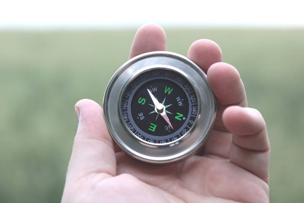Старый классический компас навигации в руке на естественном фоне как символ туризма с компасом, путешествия с компасом и на открытом воздухе мероприятий с компасом - Фото, изображение