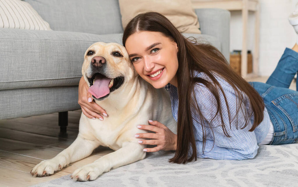 Fiatal boldog nő kutyával a padlón fekszik - Fotó, kép