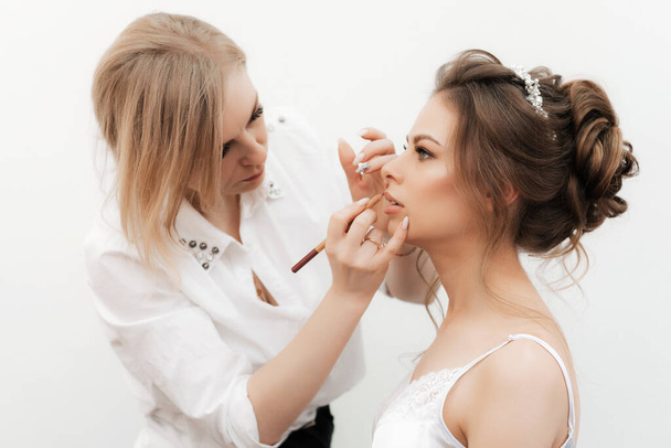 Maquillaje artista compone y pinta los labios de las novias con un lápiz
 - Foto, imagen
