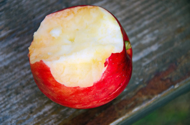 Укусил красное яблоко на деревянном фоне, укусил красное яблоко крупным планом
 - Фото, изображение