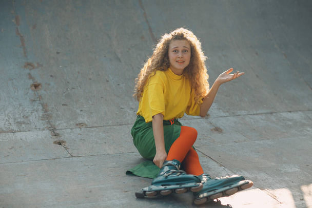 Young woman girl in green and yellow clothes going roller skate - Photo, Image