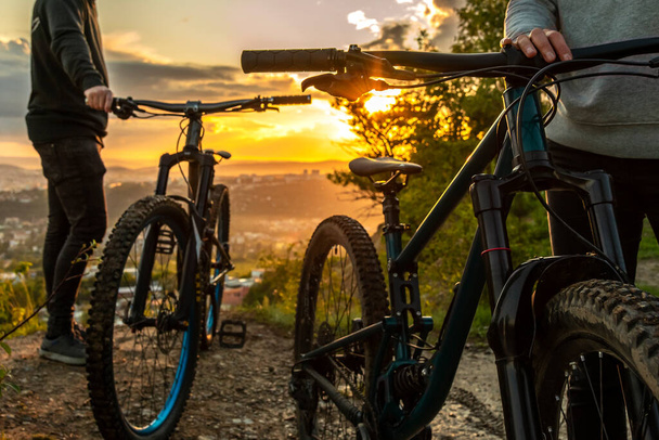 Een paar mountainbikes bij zonsondergang op de achtergrond van de stad. Reizen op mountainbike in de natuur. Fietsvakantie. - Foto, afbeelding