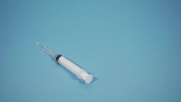 White syringe falls on the blue floor - Filmati, video