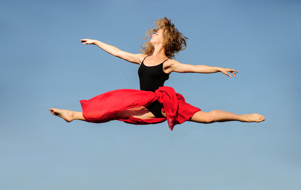 Professional ballet dancer jumping with red fabric on sunset sun - Photo, Image