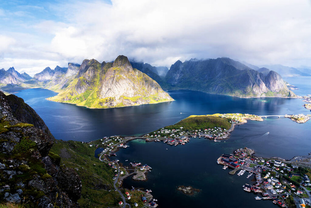 Sunny aerial panoramic view on stunning mountains and village of Reine in Lofoten islands, Norway from Reinebringen ridge. Scenic vista with a rainbow and rugged peaks. - Photo, Image