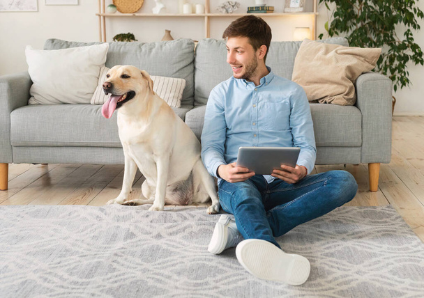 Young man at home with a tablet and labrador - Foto, Imagem