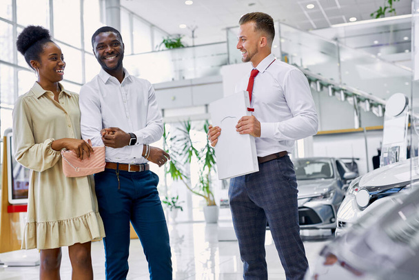 confident caucasian salesperson selling cars at car dealership - Photo, Image