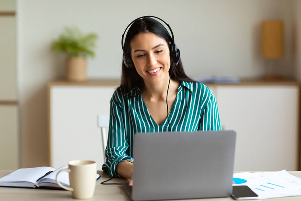 Woman In Headset Making Video Call Sitting At Laptop Indoor - 写真・画像