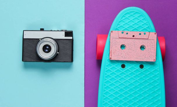 Retro set with blue skateboard with audio cassette and retro camera on colored background. Studio shot. Youth lifestyle. Top view - Fotoğraf, Görsel