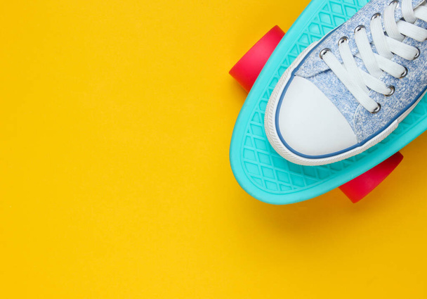 Hipster spor ayakkabıları kaykayın üstünde üstten sarı arka planda. Minimalizm moda kavramı. Boşluğu kopyala - Fotoğraf, Görsel