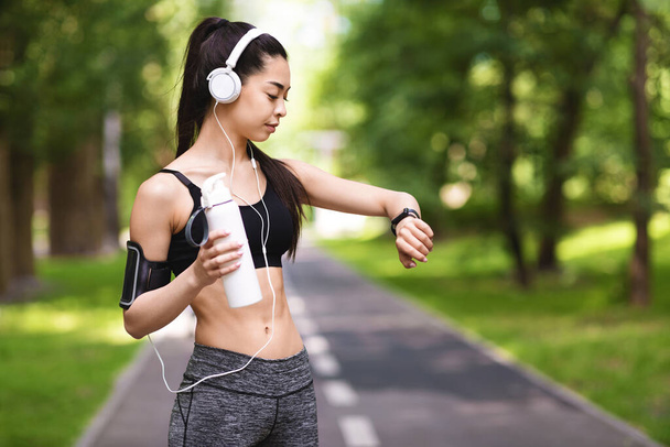 Fitness Tracker Concept. Sporty Asian Girl Looking At Smartwatch On Her Wrist - Zdjęcie, obraz