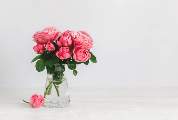 Romantic bouquet of pink roses in a glass vase on a white background.  Place for text. - 写真・画像
