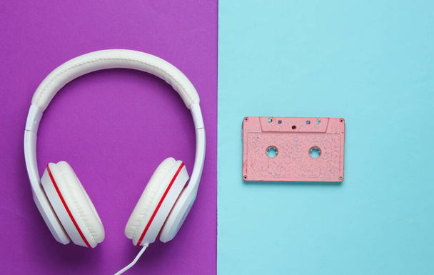 Audio cassette and headphones on purple blue background. Retro music concept. Vintage background. Disco party. Top view - 写真・画像
