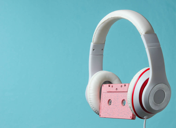 White classic wired headphones with audio cassette isolated on blue background. Retro style. 80s. Minimalistic music concept. - Photo, Image
